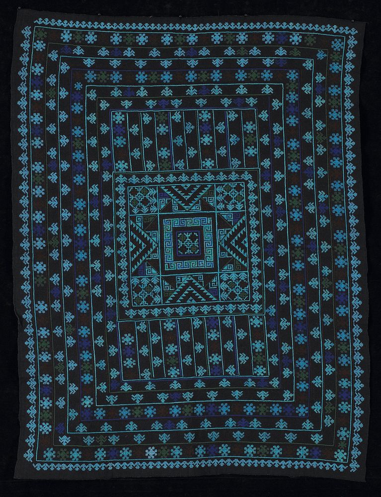 indigo fabric; cross-stitched in seven concentric bands around center square; color include blue, purple, brown and green.…