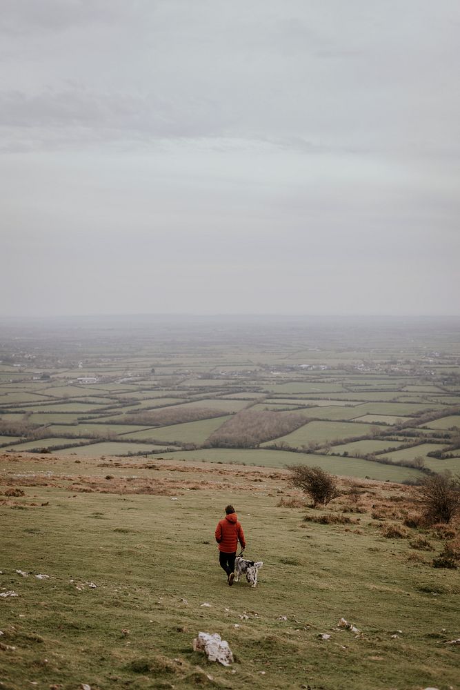 Man walking dog on hill photo