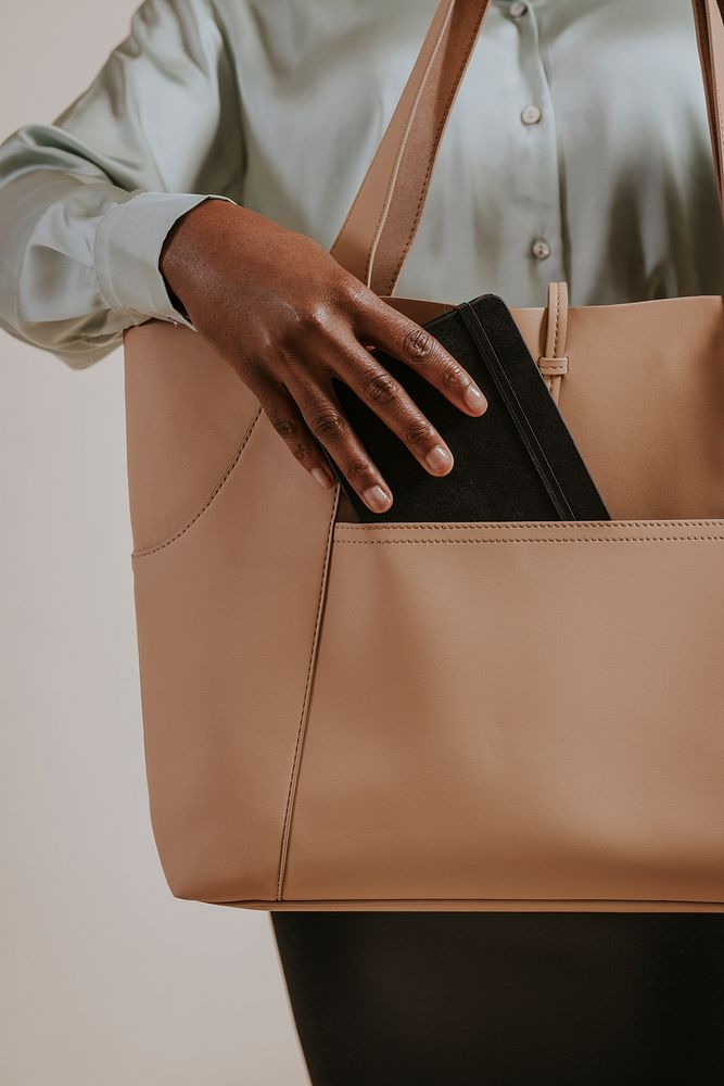 Businesswoman putting smartphone in handbag's pocket