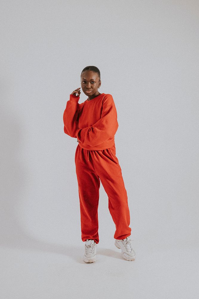 Black woman in orange sweater, sweatpants, street fashion