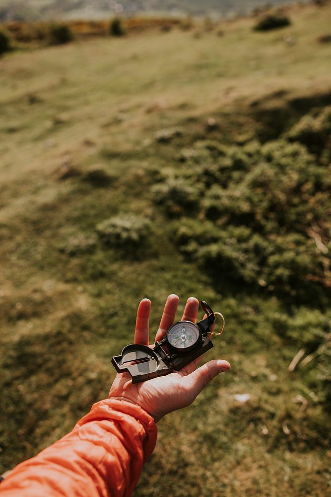 Hiker holding compass on hill photo
