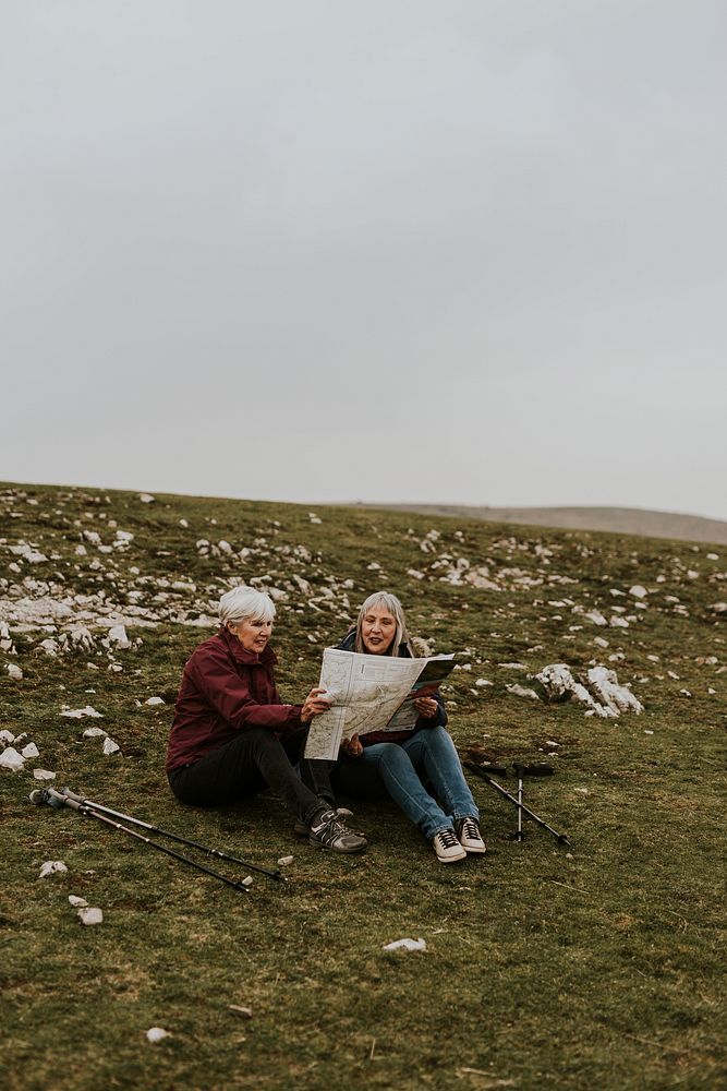 Senior women looking at map, sitting on the hill