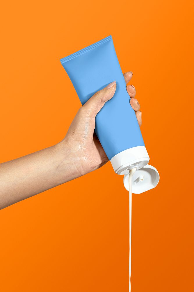 Hand squeezing cream from blue skincare tube