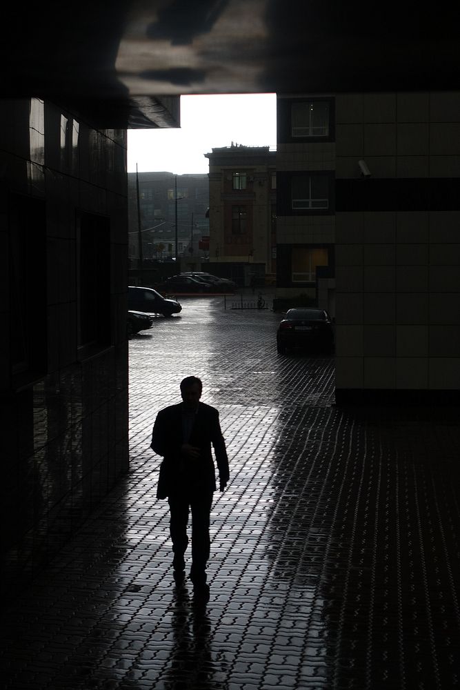 Man walking through buildings. Original public domain image from Flickr