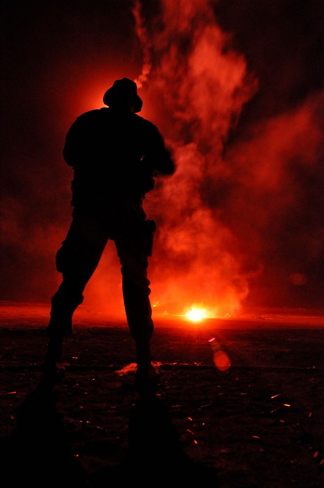 A flare illuminates a U.S. Navy Basic Underwater Demolition/SEAL (BUD/S) third phase trainee during a night shoot on San…