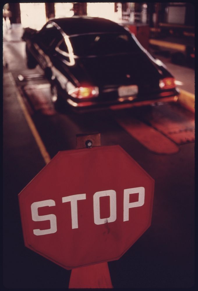 Stop Sign Where Motorists Halt Their Vehicles and Turn Them over to Employees at an Auto Emission Inspection Station in…