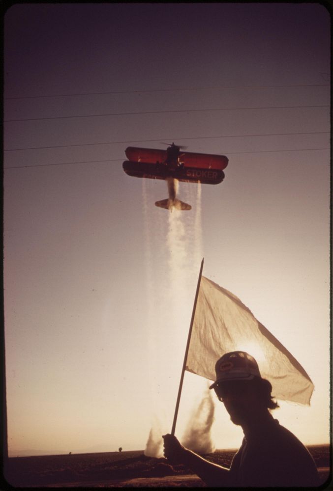 Crop duster plane and "flag man" near Calipatria in the Imperial Valley, May 1972. Photographer: O'Rear, Charles. Original…