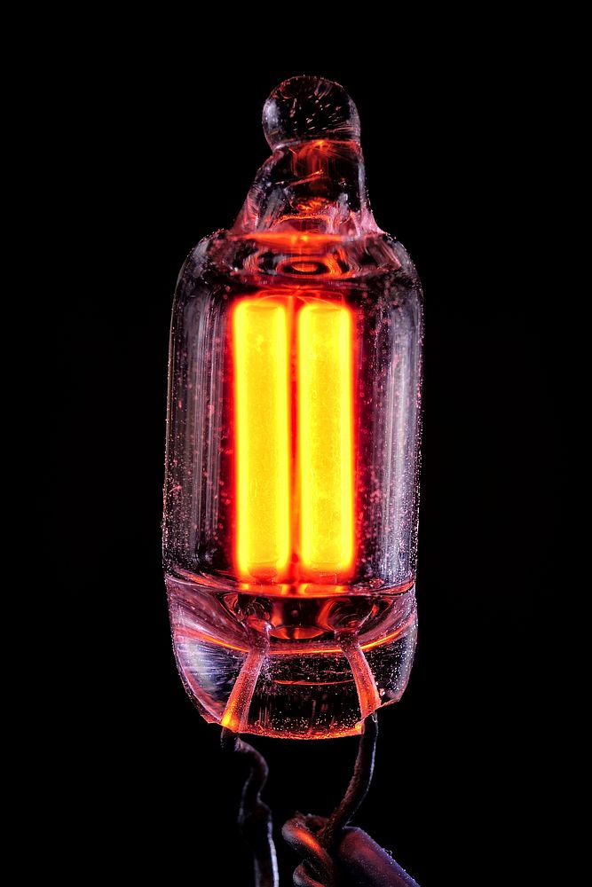 Close-up view of an NE-2 (5mm diameter) type neon lamp. Both electrodes appear to glow simultaneously due to being powered…