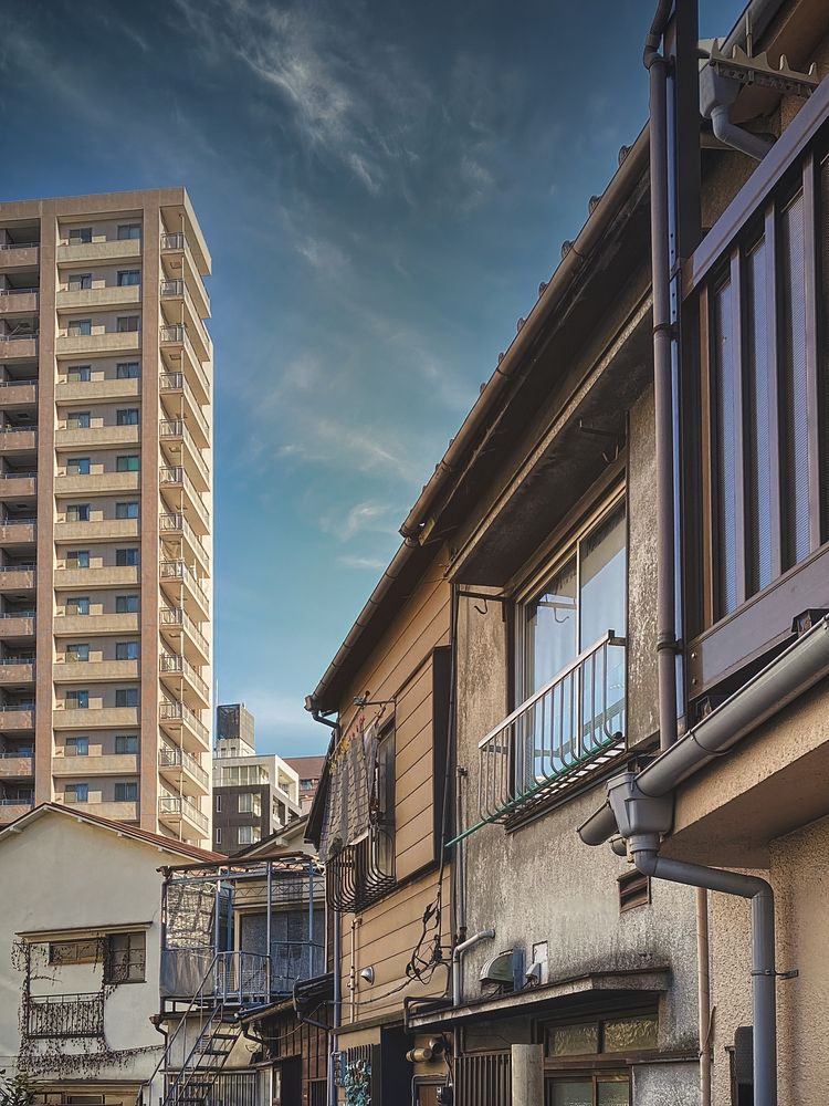 Inner City Residences, Tokyo, JapanLooking past an aging house to see a residential tower, another old house, and blue sky…