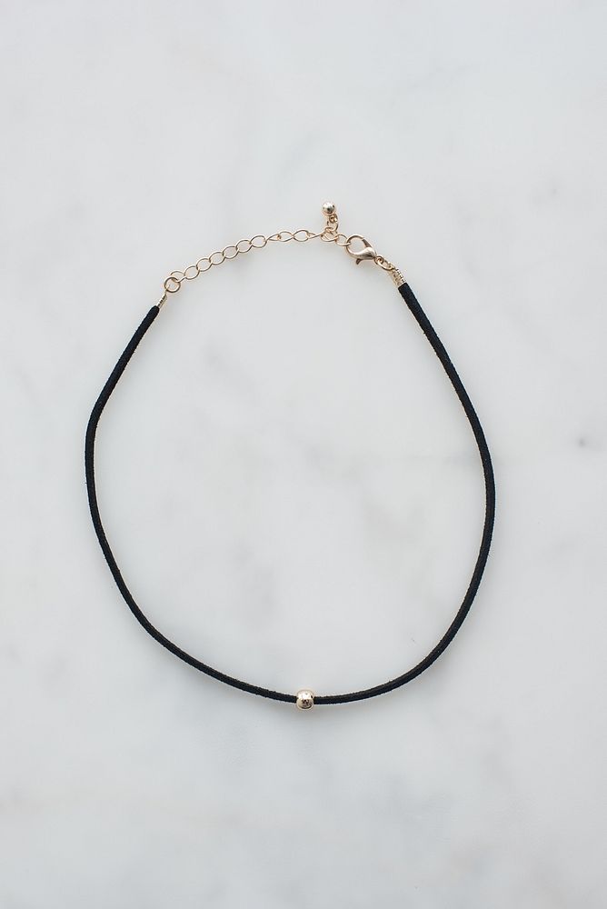 Black choker necklace with gold bead.
