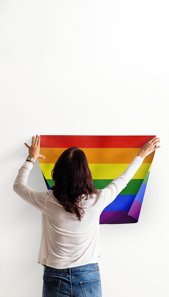 Pride flag iPhone wallpaper, woman decorating wall