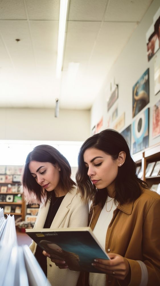 Two hispanic women publication reading adult. 