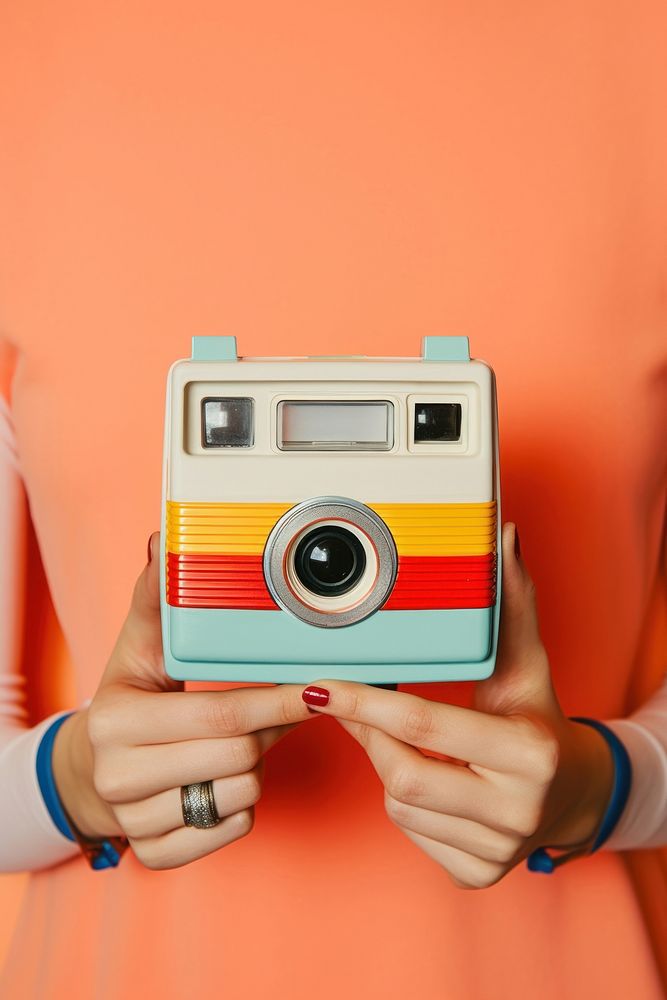 A person holding a small retro-style Polaroid camera photo hand red. AI generated Image by rawpixel.