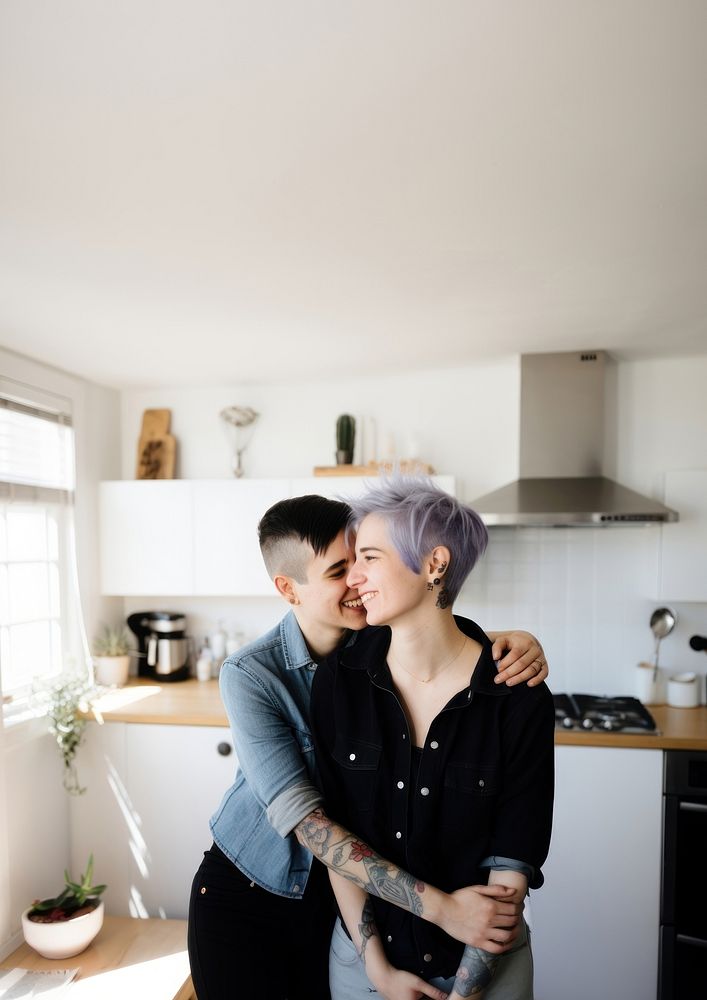 Smiling lesbian couple portrait kissing kitchen. 