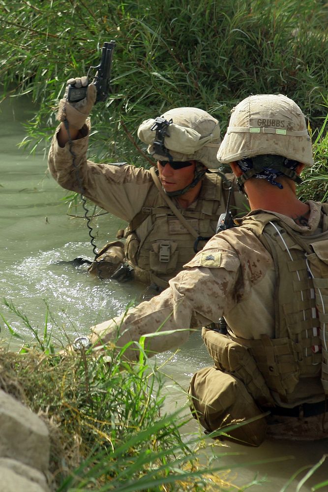 U.S. Marine Corps Lance Cpl. Helmut Eggl holds his M-9 Beretta handgun above water as he crosses a canal July 26, 2009…