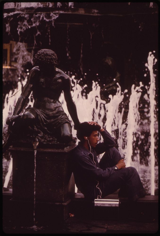 At the Tyler Davidson Fountain, in Fountain Square Downtown Cincinnati's Popular Public Plaza, a Young Man Listens to the…