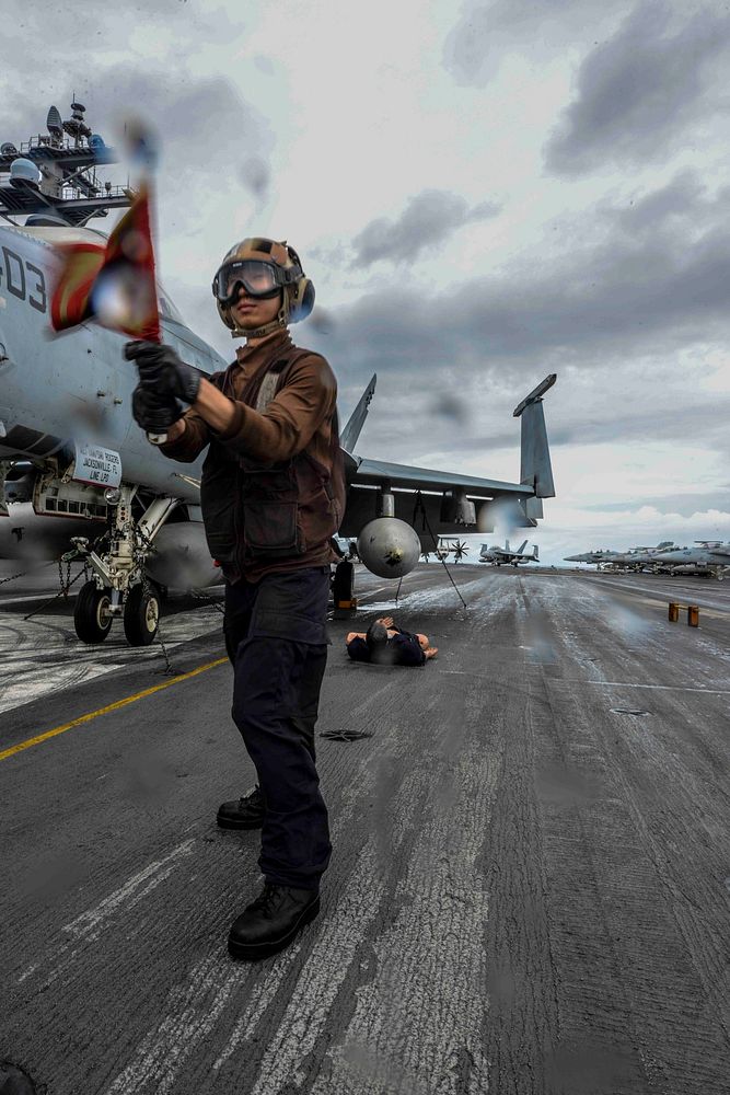 A U.S. Sailor assigned to Air Department simulates an aircraft fire during a mass casualty drill on the flight deck of the…