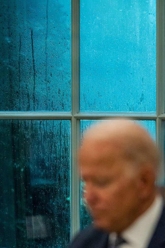 Rain is seen through the windows as President Joe Biden meets with staff to review remarks he will deliver about the…