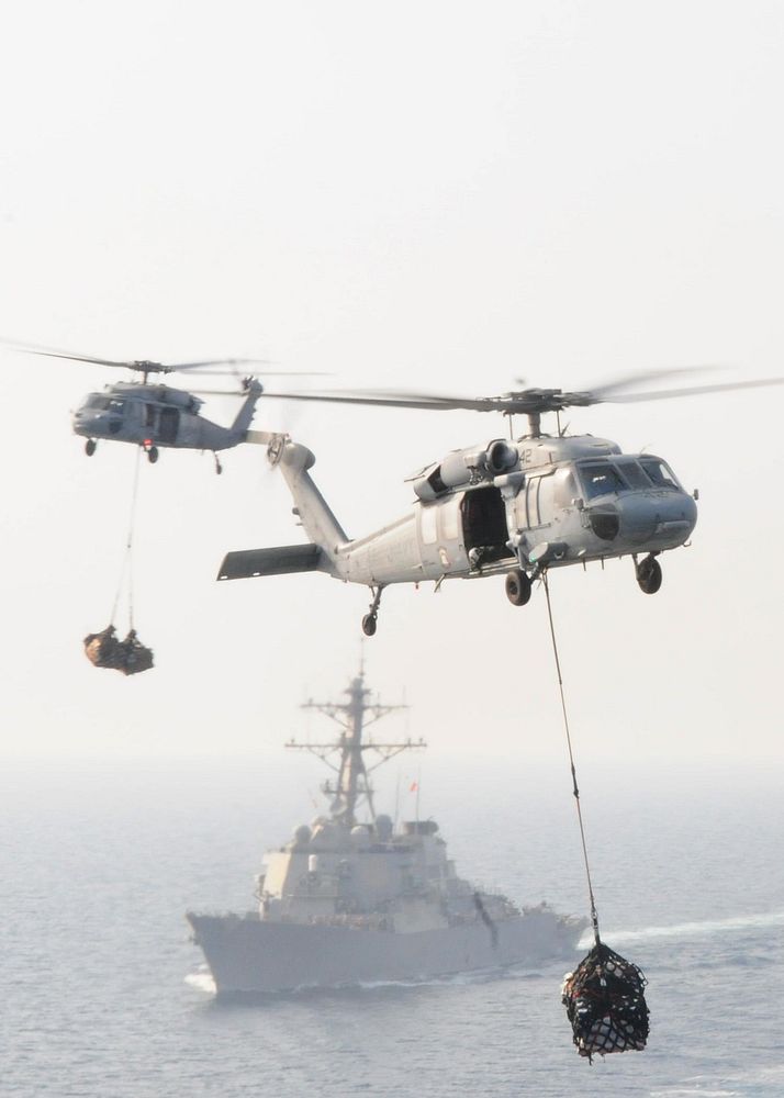 U.S. Navy MH-60S Knighthawk helicopters assigned to Helicopter Sea Combat Squadron (HSC) 23 transfer supplies from the fast…