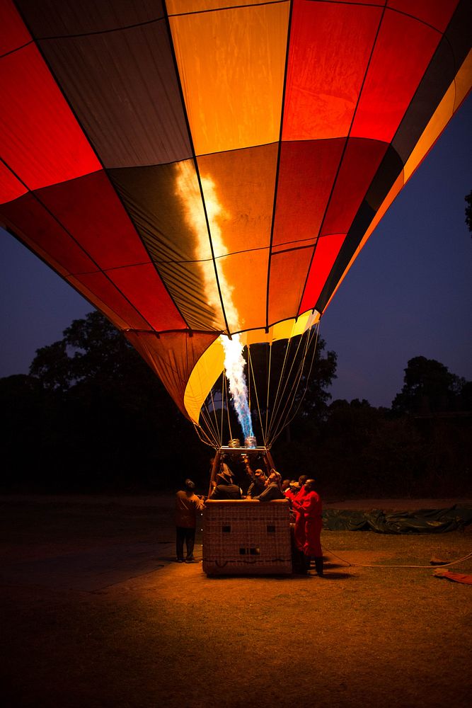 People watch a gas is flared into a Governor's Balloon Safari hot air balloon in preparation for a flight over the Masai…