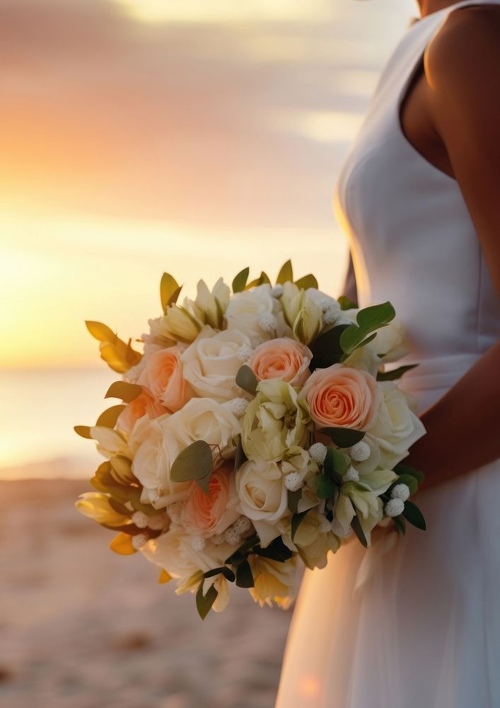 Closeup groom and bride have bouquet at the sunset beach, focus on bouquet.  