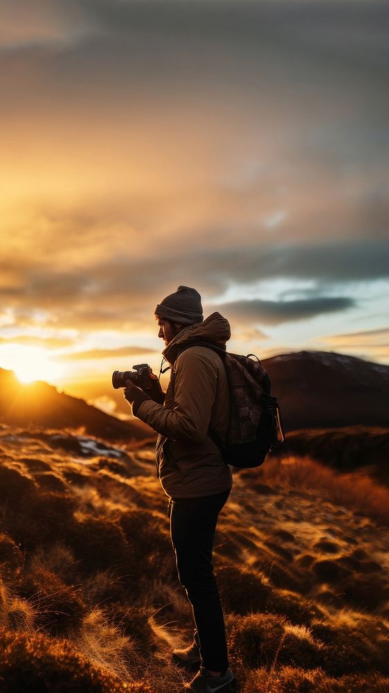 front-left view Photo of a man holding camera, taking picture in the wild in a chilly day. 