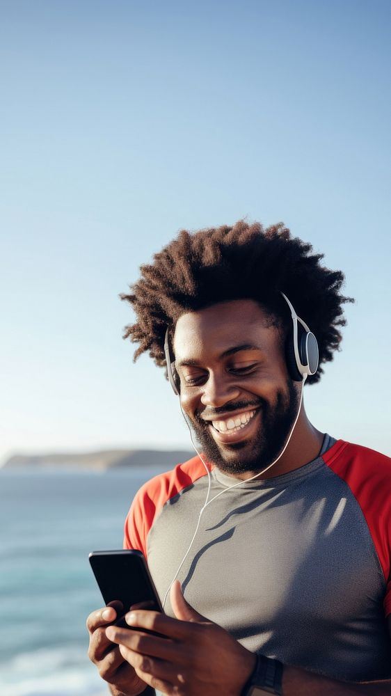 Photo of Portrait of a smiling afro-american sports man stretching his muscular arms before workout by the sea.  