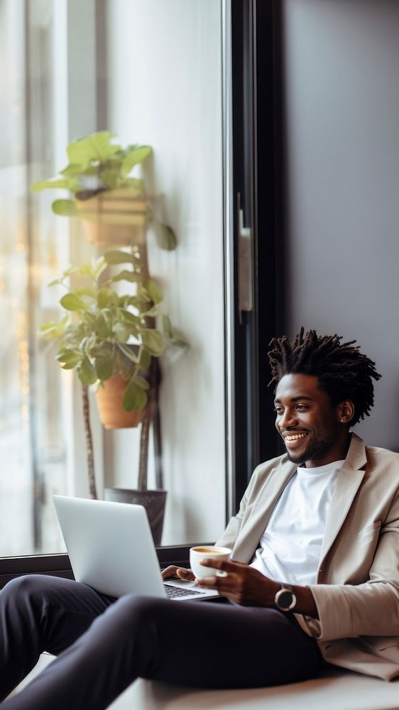 photo of happy african american man drink coffee while working laptop at home. AI generated Image by rawpixel. 
