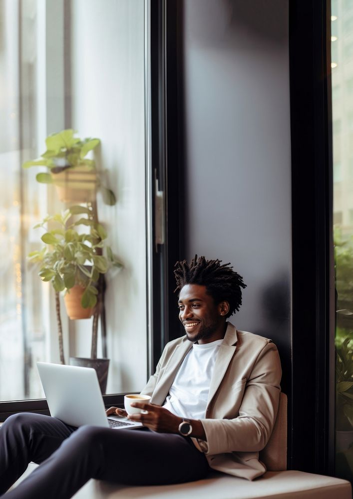 photo of happy african american man drink coffee while working laptop at home. AI generated Image by rawpixel. 