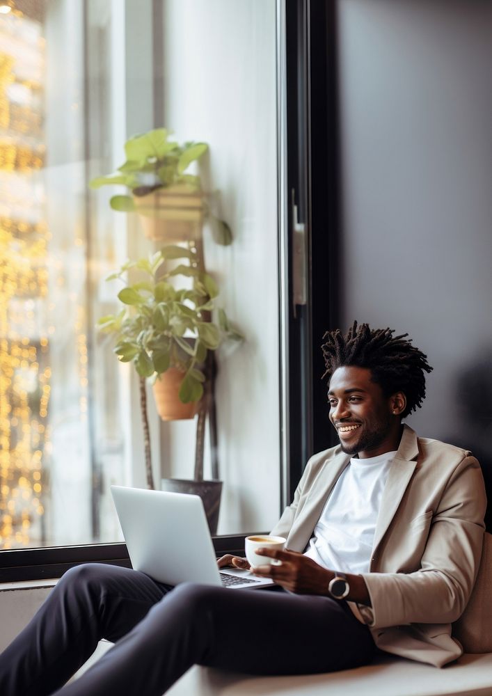 photo of happy african american man drink coffee while working laptop at home. AI generated Image by rawpixel. 
