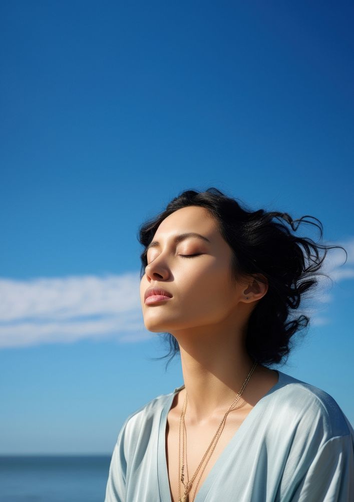 photo of woman praying with bluesky on the sea with blurred vision. AI generated Image by rawpixel. 