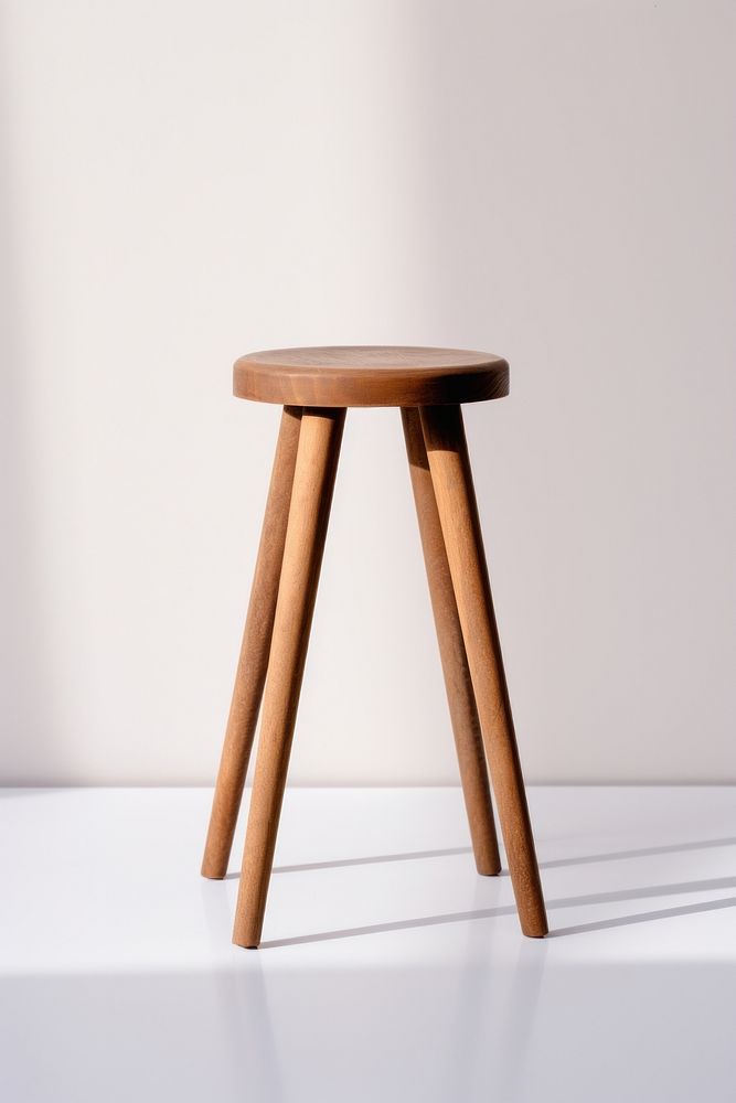 A wooden stool with four legs, simple design. Wooden stool stands on a white surface. Light wooden stool, minimalistic…