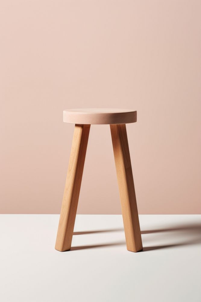 Minimalist wooden stool with three legs. Simple stool design. Wooden stool against a neutral background. Ideal for modern…