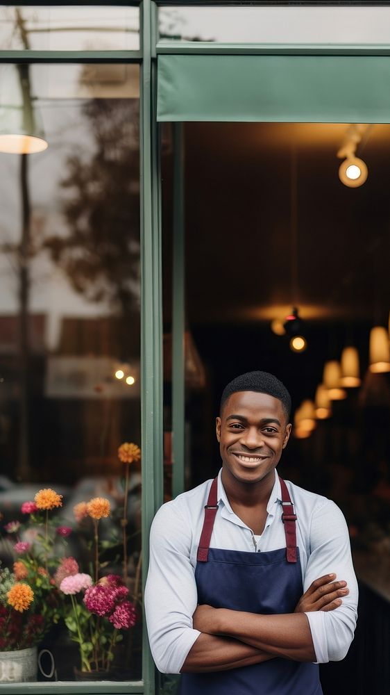 Photo of a cheerful small business owner standing and smiling in front of their shop.  