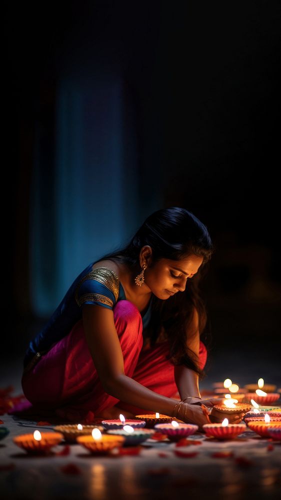 close up shot of Indian woman hand lighting diyas on Rangoli decorations on floor in Diwali festival. AI generated Image by…