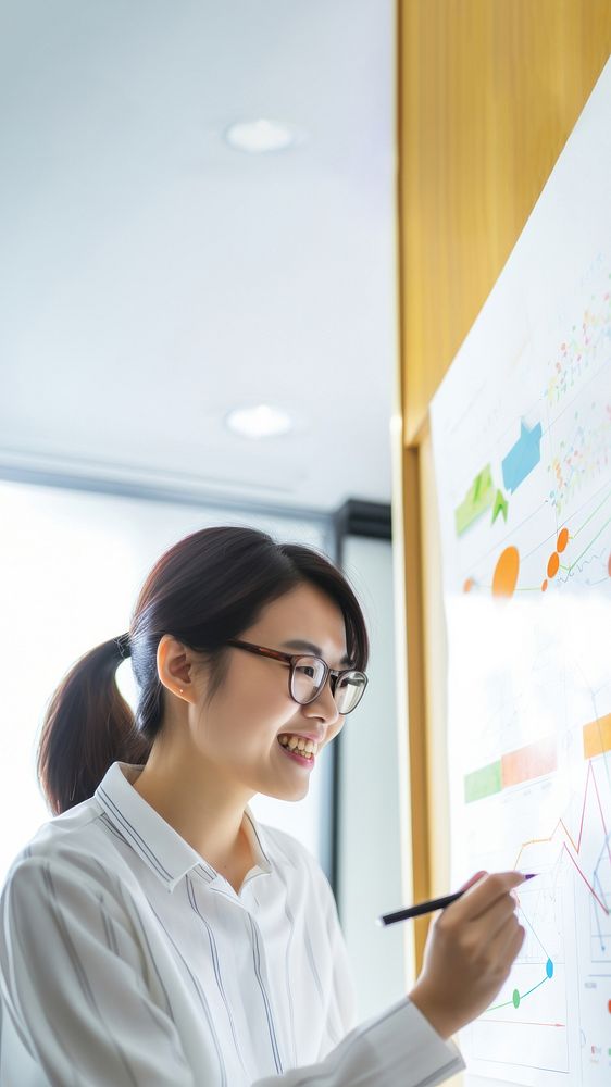 photo of asian women wearing glasses writing a chart on a whiteboard. 