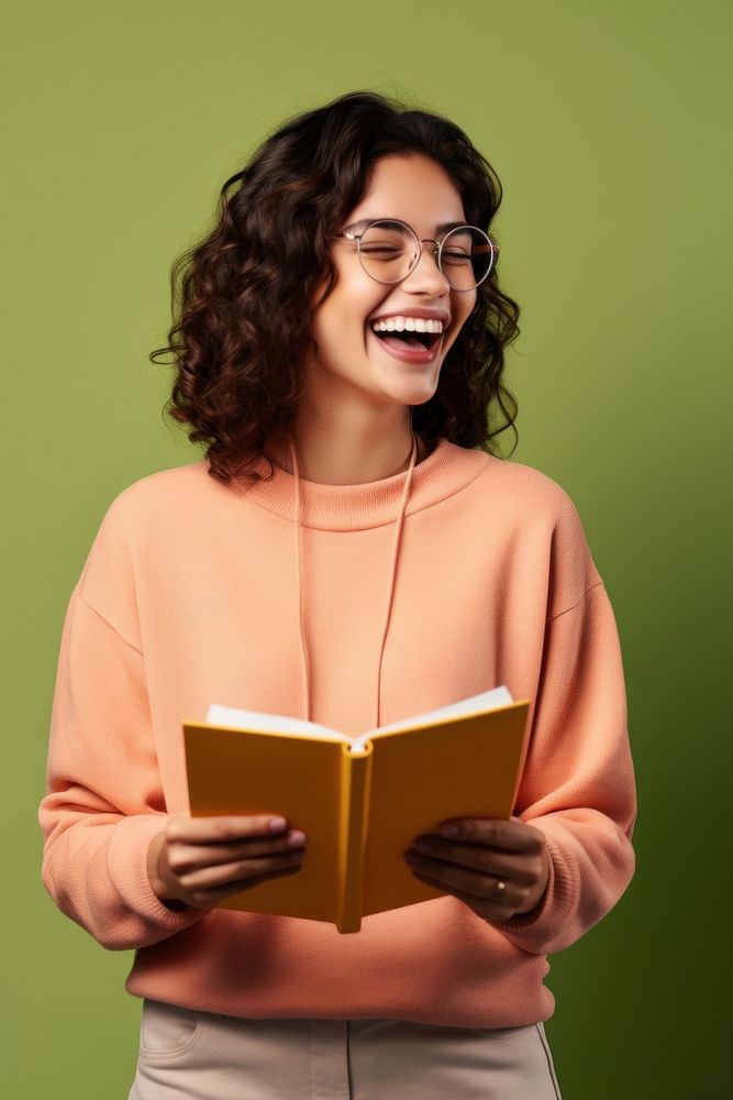 Student holding a book publication laughing reading. AI generated Image by rawpixel.
