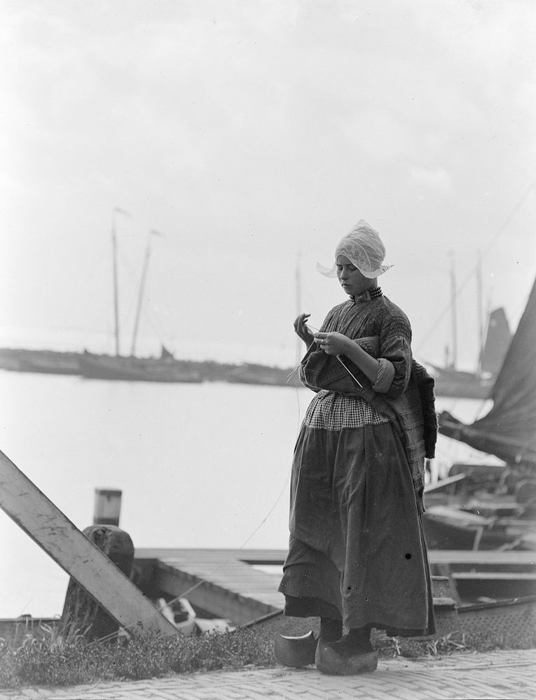 Young woman knitting by canal, Netherlands (1906-1917) by George Crombie.