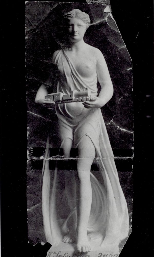 Statue of female figure holding model train (circa 1910).