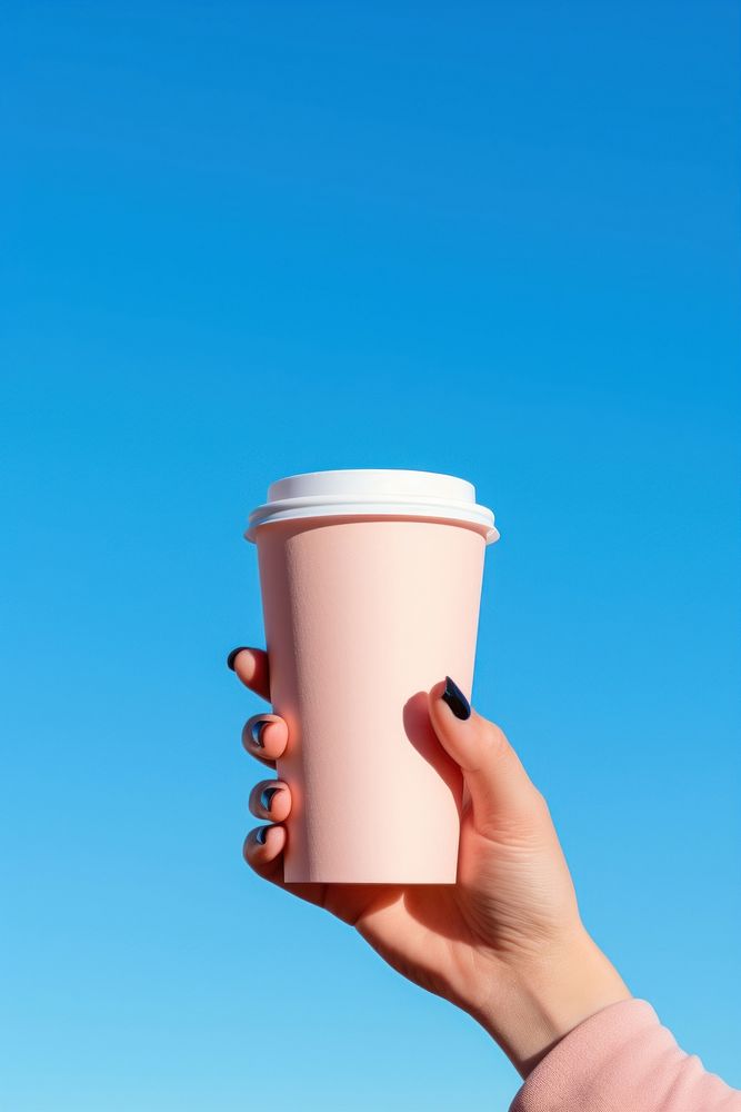 Hand holding disposable coffee cup against a clear sky drink mug day. AI generated Image by rawpixel.