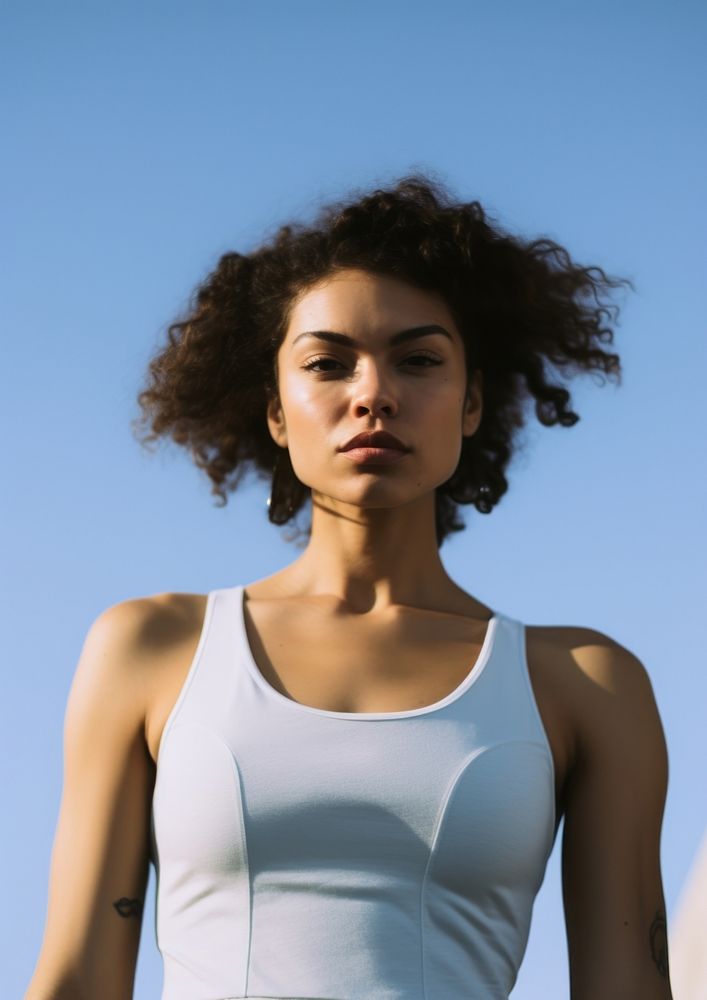 Black young woman wearing a white tank top and back cap standing adult blue. AI generated Image by rawpixel.