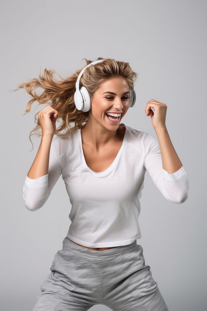 A Beautiful woman wearing gym clothes and headphones dancing happily and cheerful listening laughing shouting. AI generated…