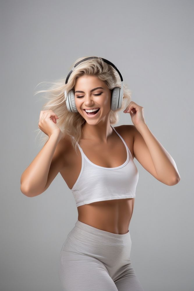 A Beautiful woman wearing gym clothes and headphones dancing happily and cheerful listening smiling smile. AI generated…