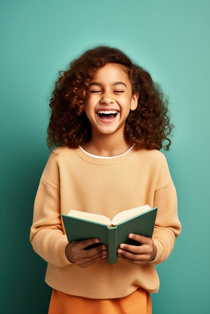 Girl holding a book laughing reading school. AI generated Image by rawpixel.