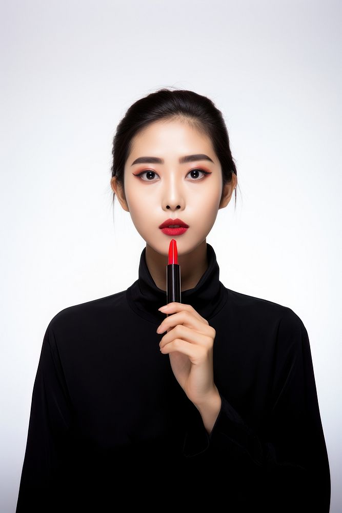 Beautiful trendy young asian female fashion model putting makeup and lipstick portrait photo white background. AI generated…