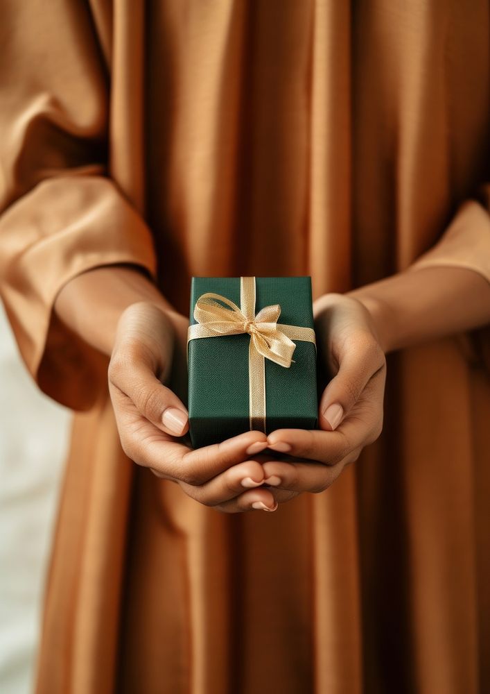 Dark green tiny gift box holding hand celebration. AI generated Image by rawpixel.