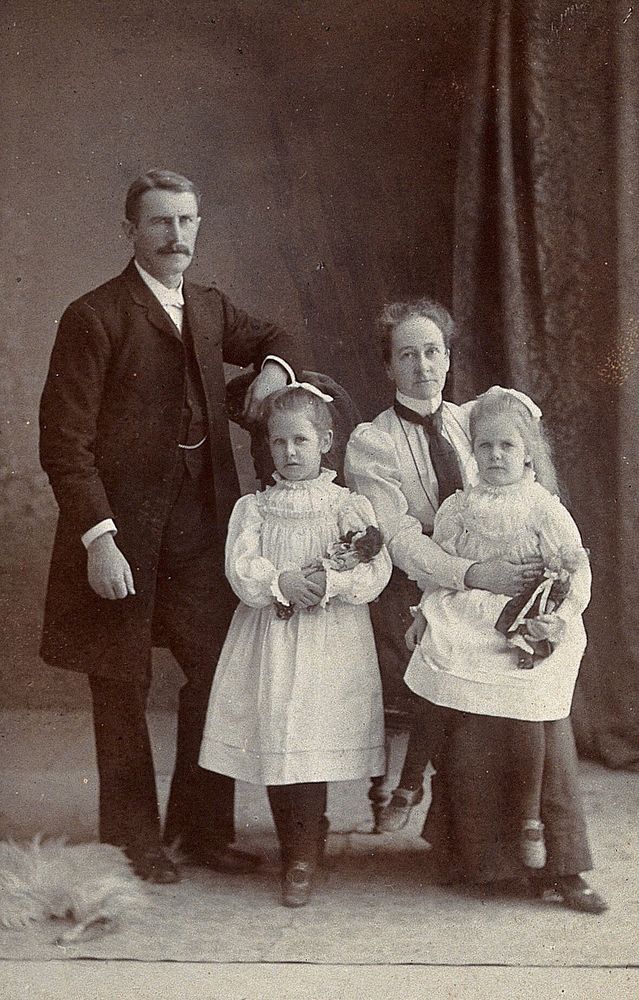 Unidentified family with two girls holding dolls. Photograph by Priya Lall & Co, Agra.