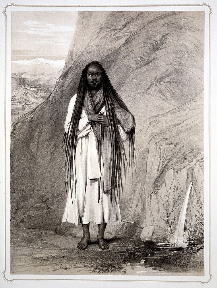 A Hindu man (sadhu) with long hair, cloak and walking stick stands by a rock from which water springs. Lithograph by L.C.…