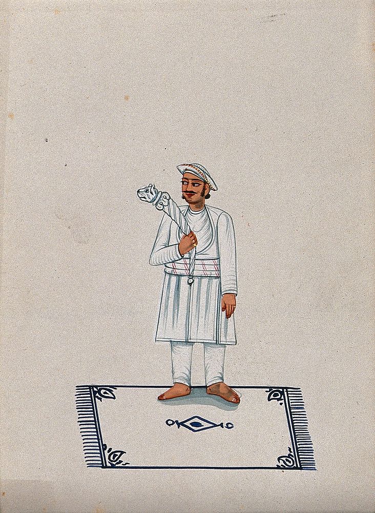 A servant standing on a carpet and holding a stick with a tiger head. Watercolour by an Indian artist.