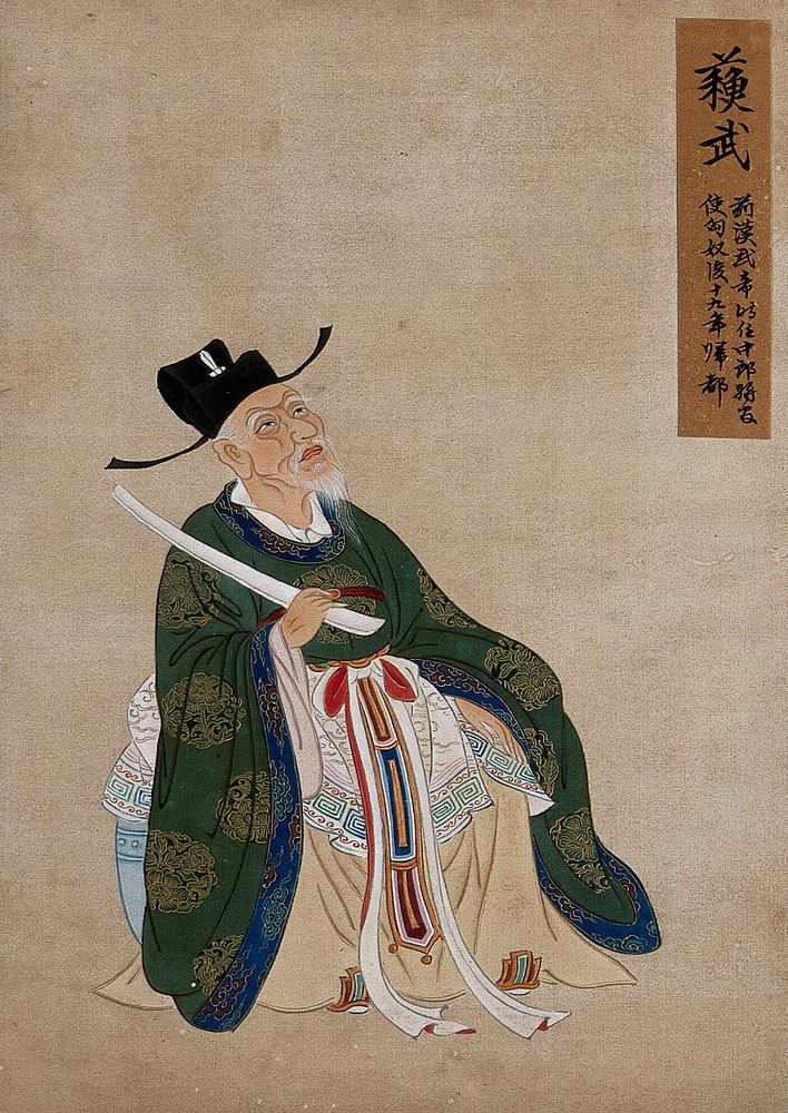A Chinese figure, seated, wearing green robes richly decorated with lotus flower designs in gold thread with blue border and…